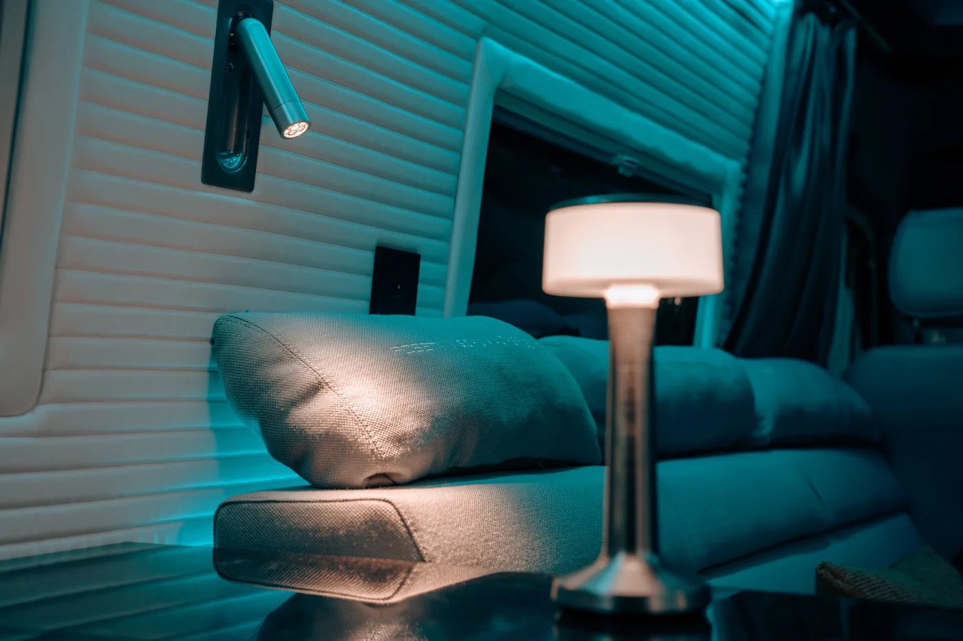 Accogliente zona salotto con divano imbottito, cuscino decorativo e una moderna lampada da tavolo che emette una luce calda.